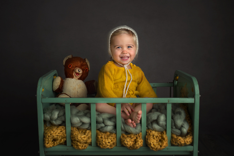 Child in antique crib with vintage animals