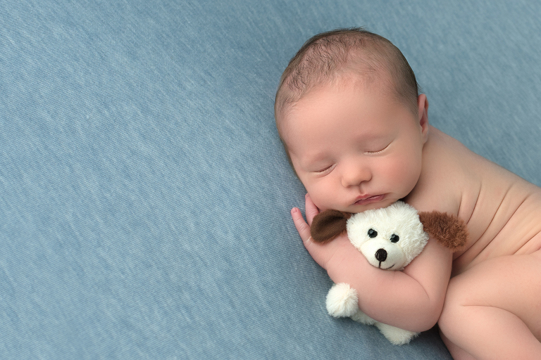 Baby boy snuggling puppy asleep.